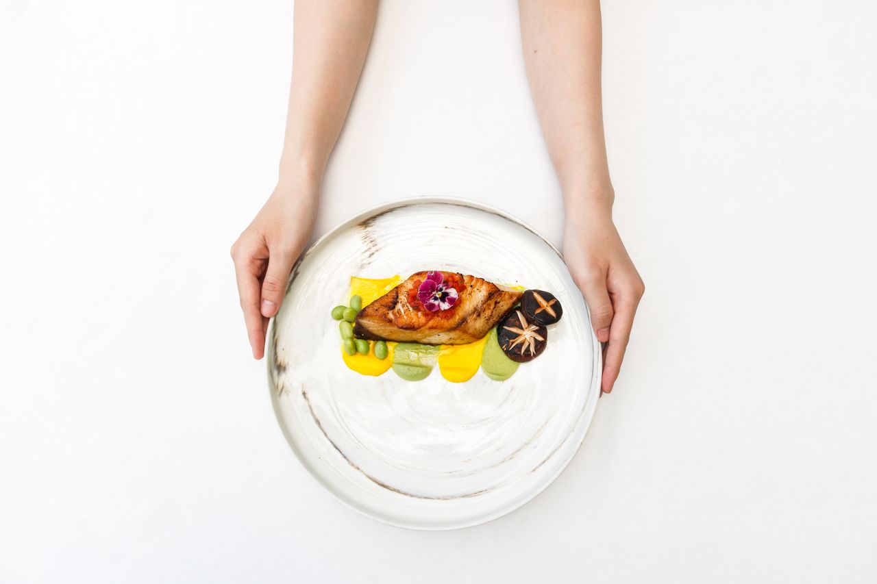 Delicious gourmet presentation with chicken, shiitake mushrooms, and edible flower on a white plate.